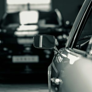 A close-up shot of a classic car's side mirror, exuding elegance and style in a monochrome setting.